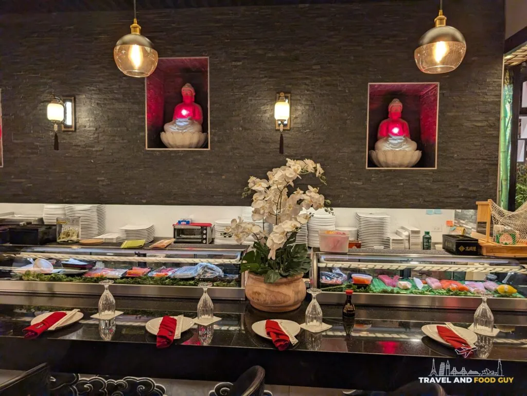 The sushi bar at Wu's House Kildeer with white orchids on the counter and red lit niches on the wall behind it.
